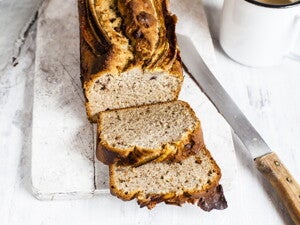 Κομμένο ψωμί μπανάνας σε ξύλινη επιφάνεια με μαχαίρι δίπλα.