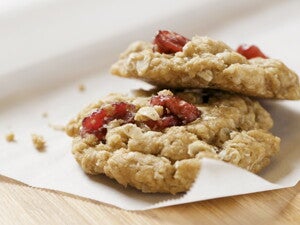 Μπισκότα βρώμης με κομμάτια μούρων πάνω σε χαρτί ψησίματος.