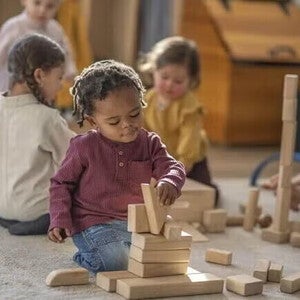 Παιδιά παίζουν με ξύλινα τουβλάκια σε αίθουσα τάξης.