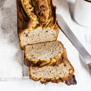 Κομμένο ψωμί μπανάνας σε ξύλινη επιφάνεια με μαχαίρι δίπλα.