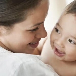 Μητέρα κρατά μωρό σε φωτεινό δωμάτιο, τρυφερή στιγμή.