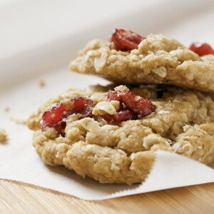 Μπισκότα βρώμης με κομμάτια μούρων πάνω σε χαρτί ψησίματος.