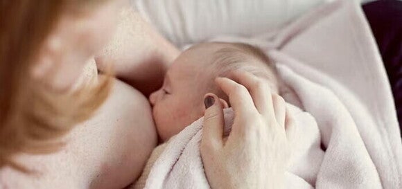 Ένα μωρό σκεπασμένο με κουβερτάκι ενώ θηλάζει στην αγκαλιά της μητέρας του. Ένα μωρό σκεπασμένο με κουβερτάκι ενώ θηλάζει στην αγκαλιά της μητέρας του.