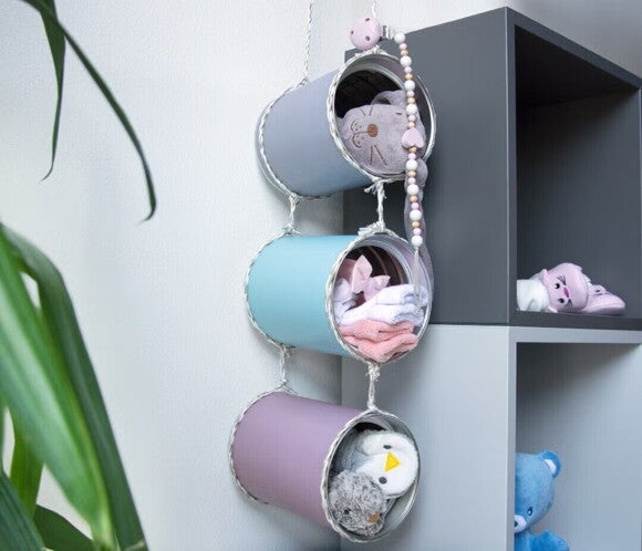 Μία συλλογή από πολύχρωμες κονσέρβες που περιέχουν παιχνίδια κρέμονται από ένα στολισμένο σκοινί. 